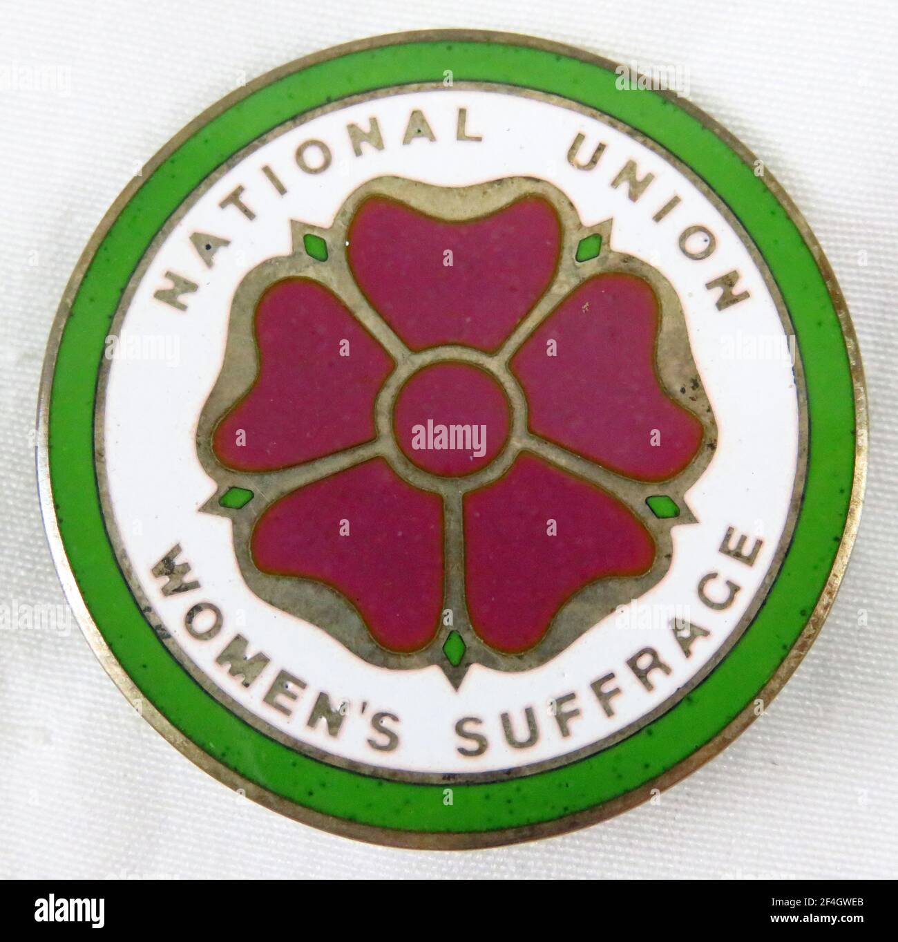 Red, green, and white enamel pin with a stylized five-petalled red rose and the text 'National Union Women's Suffrage, ' manufactured by the National Union of Women Suffrage Societies (NUWSS), for the British market, 1900. Photography by Emilia van Beugen. () Stock Photo