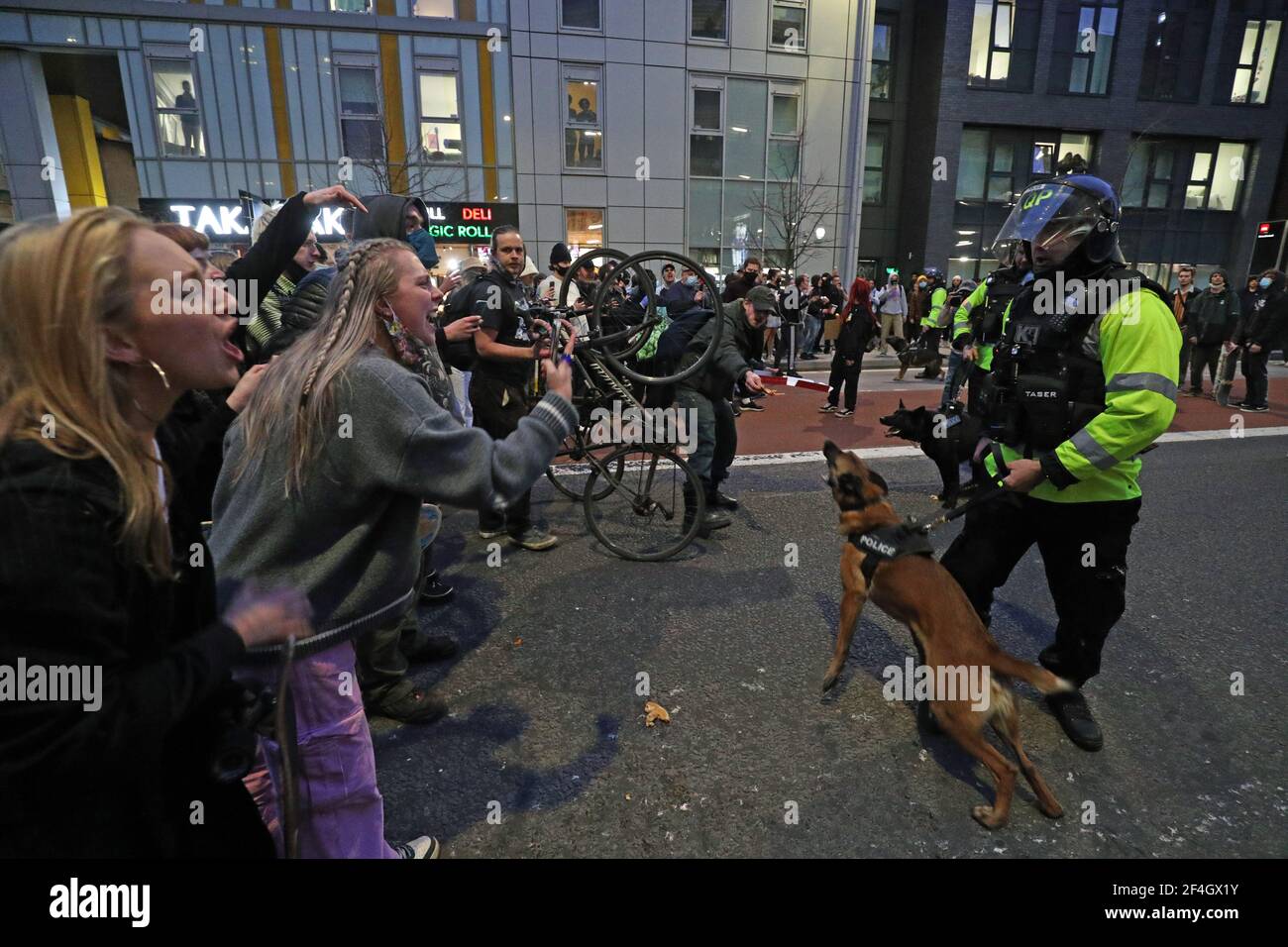 A police officer with a police dog faces protesters outside Bridewell Police Station as they take part in a 'Kill the Bill' protest in Bristol, demonstrating against the Government's controversial Police and Crime Bill. Picture date: Sunday March 21, 2021. Stock Photo