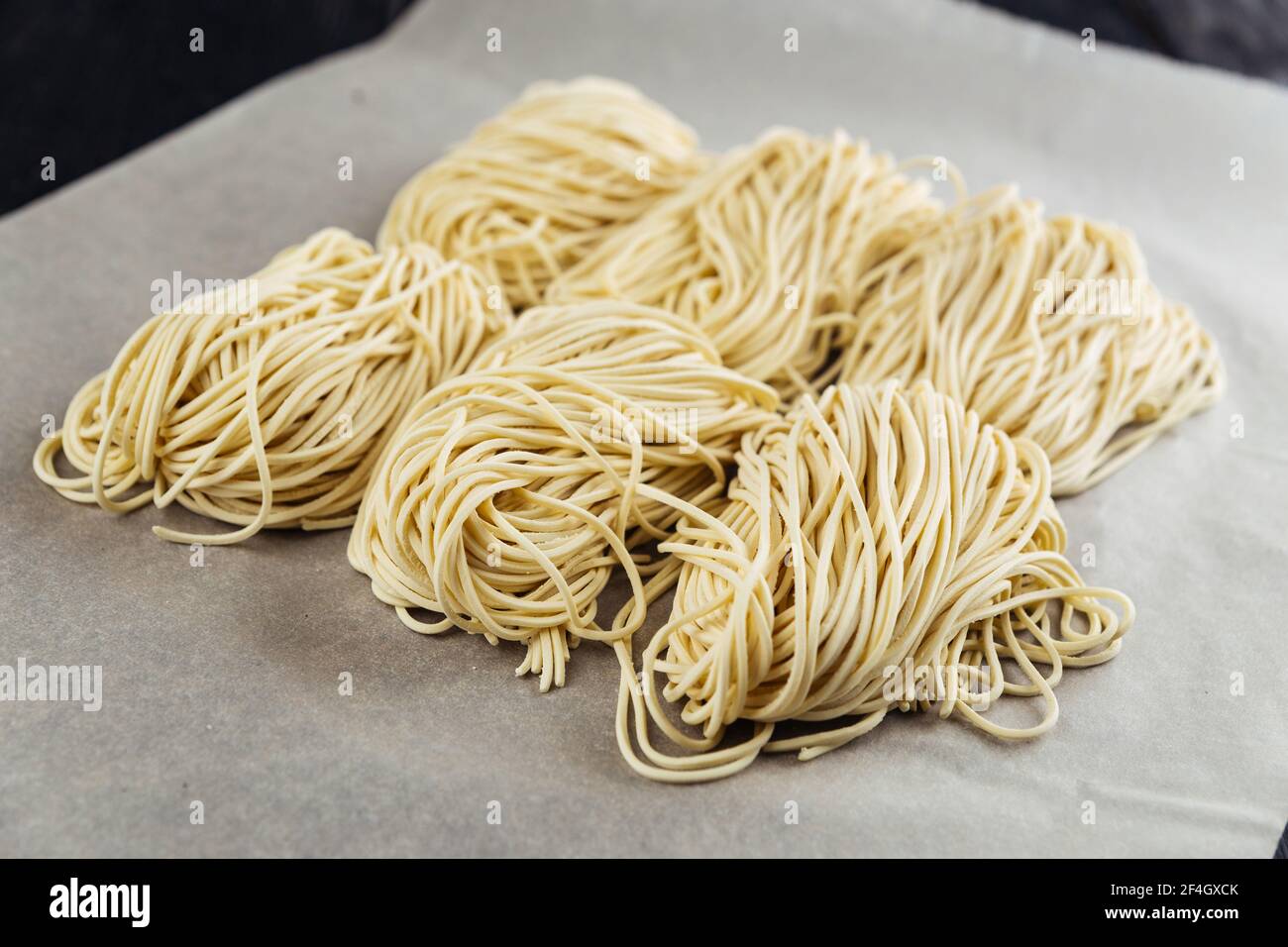 Raw egg noodle nests on the parchment paper Stock Photo