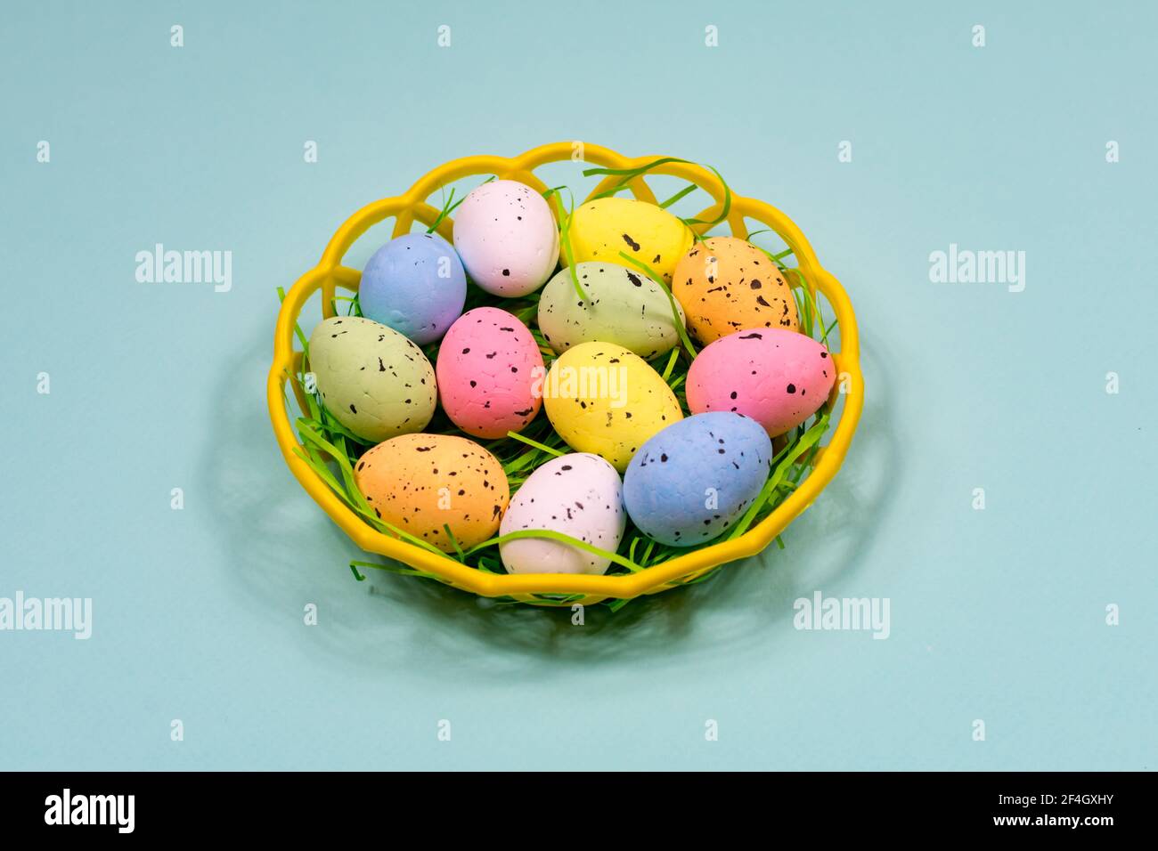Multicolored Easter eggs in a plastic basket on a blue background. Close-up. View from above. Easter. Stock Photo