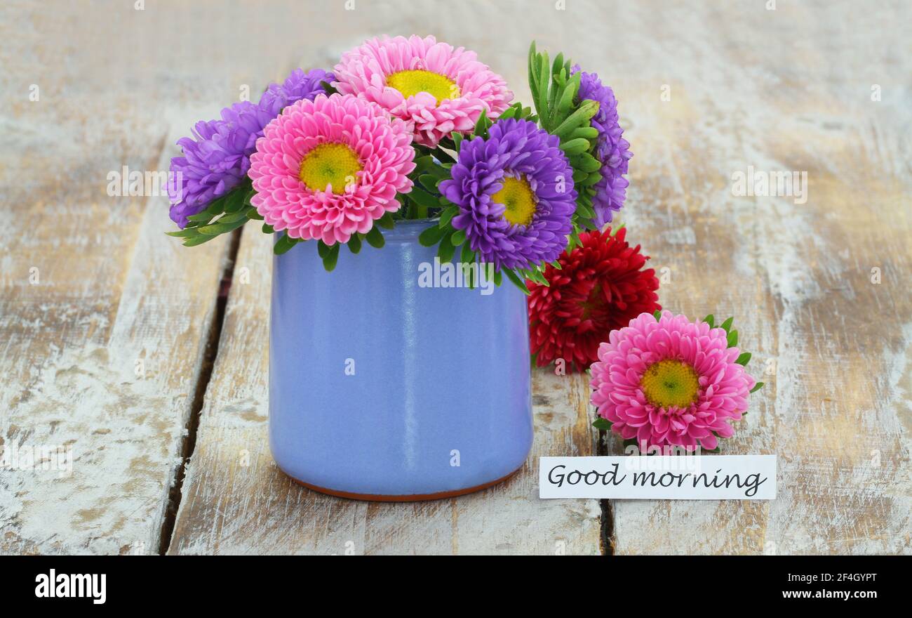 Good morning card with colorful daisy flowers in blue vase on rustic