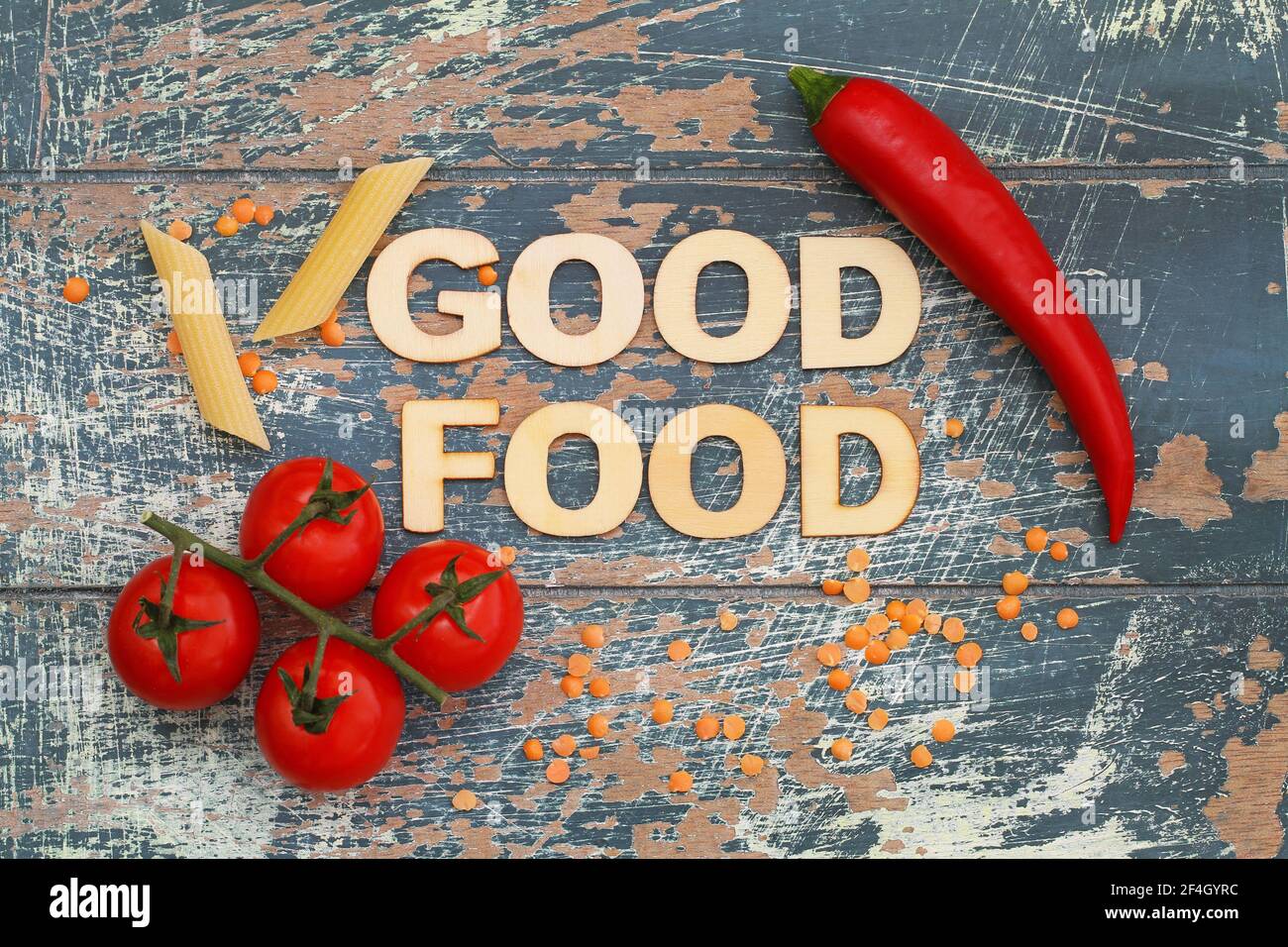 Good food written with wooden letters on rustic wood with cherry tomatoes, pasta, lentils and chili Stock Photo