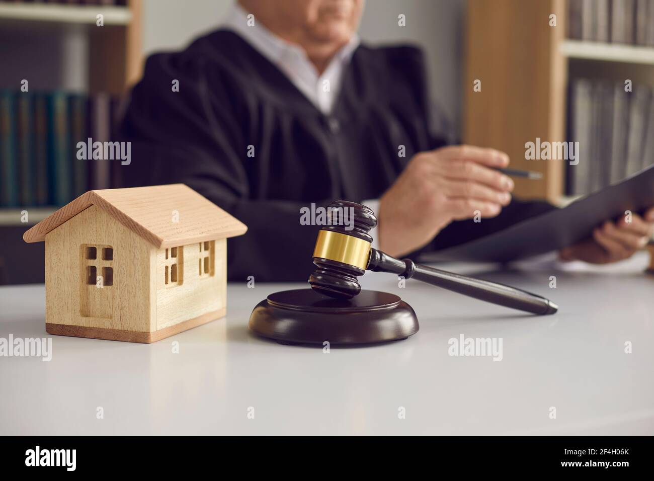Closeup of judge's gavel and little wooden toy house placed on table in court of law Stock Photo