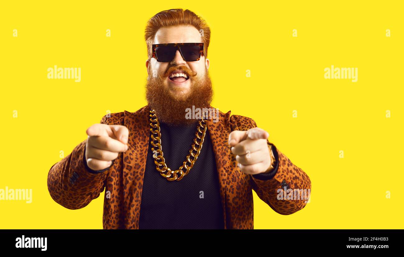 Man in gold chain and funky suit pointing fingers at camera isolated on color background Stock Photo