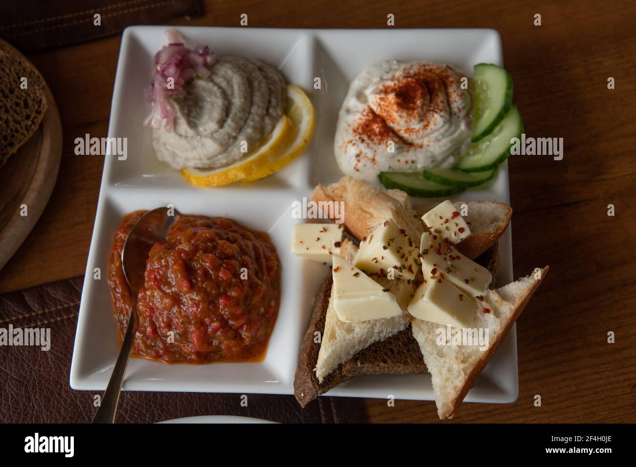 White crockery plate with mezze tasting set of assorted pate pastes and appetizers made from mashed vegetables. Bread toasts and butter pieces with sp Stock Photo