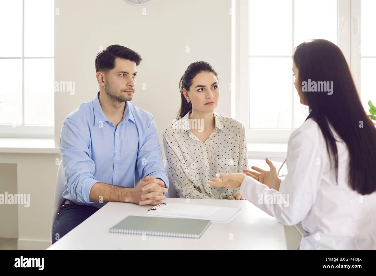 Doctor counseling millennial family couple about medical treatment at clinic Stock Photo
