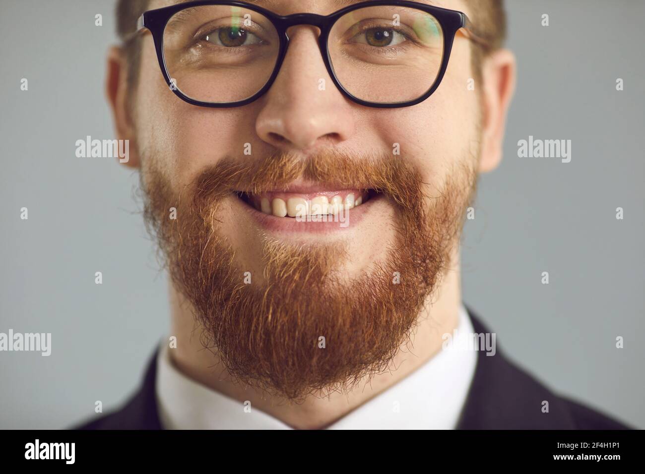 Closeup studio shot of happy smiling man in glasses with ginger beard and mustache Stock Photo