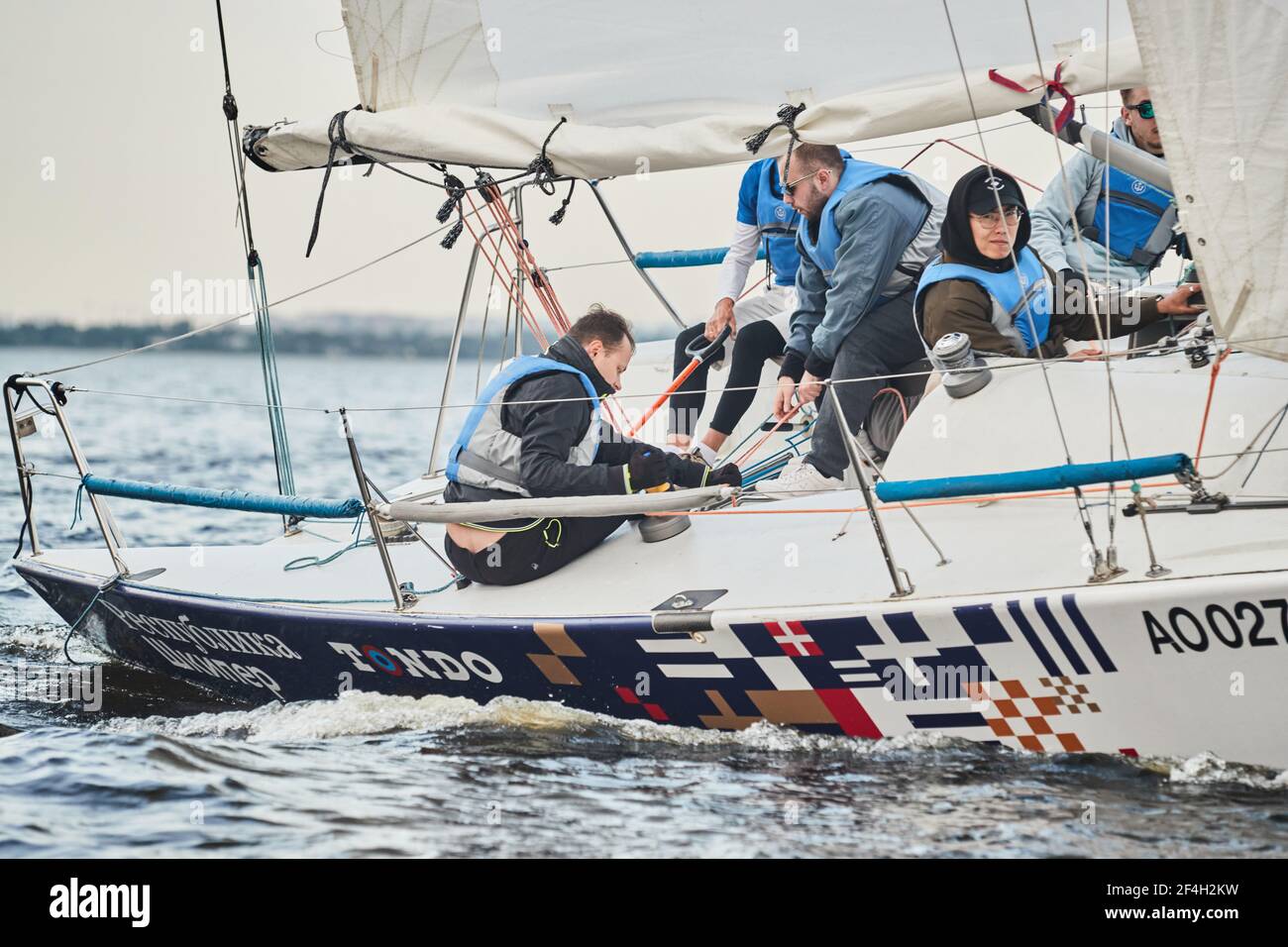 Russia, St.Petersburg, 05 September 2020: Participants of a sailing regatta on the sailboat, pull ropes, water splashes in the foreground, focus on Stock Photo