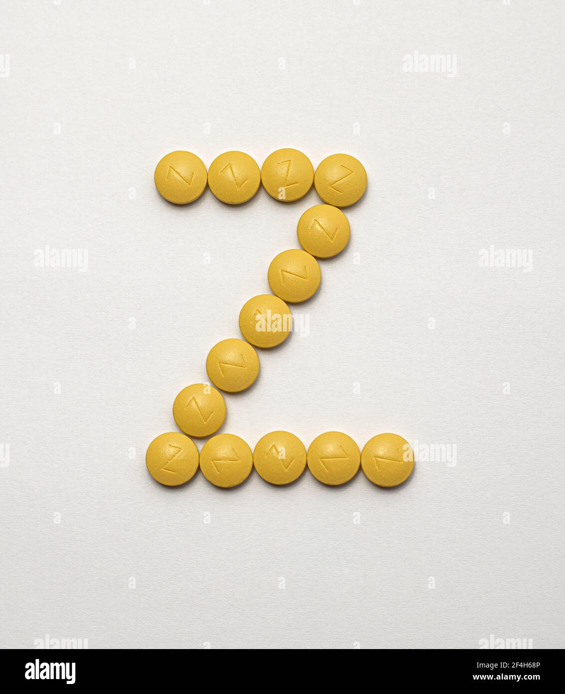 Iron in yellow tablets arranged in the letter Z on a white background Stock Photo