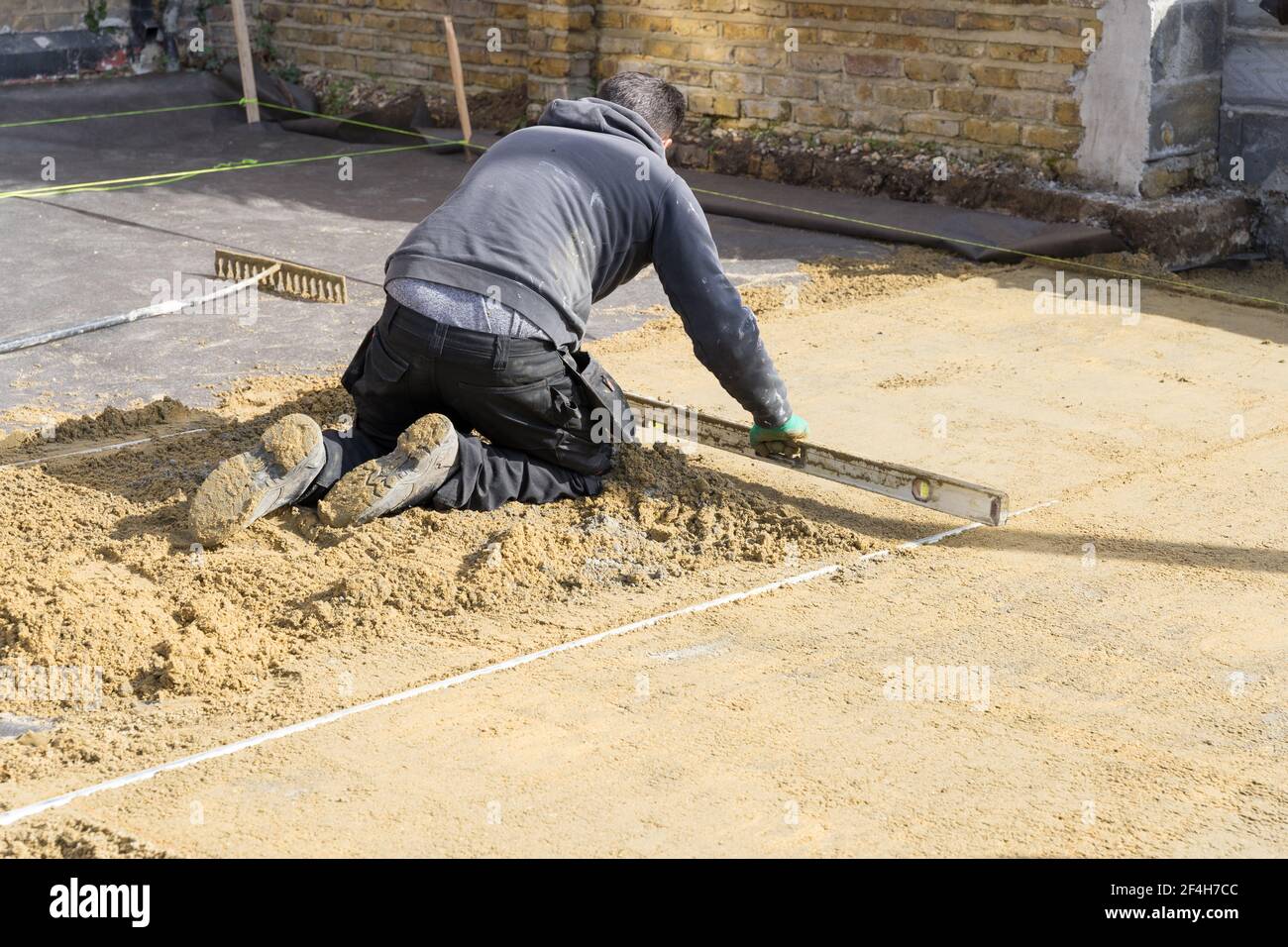 Builder levels off the base sand payer for paving Stock Photo