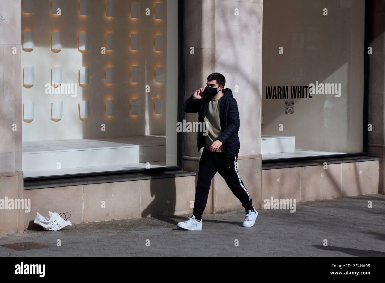 Man on phone walking past Zara window display, Barcelona, Spain. Stock Photo