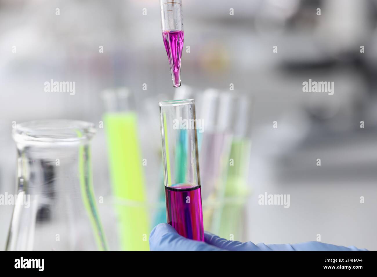 Purple liquid is dropped from pipette into test tube Stock Photo