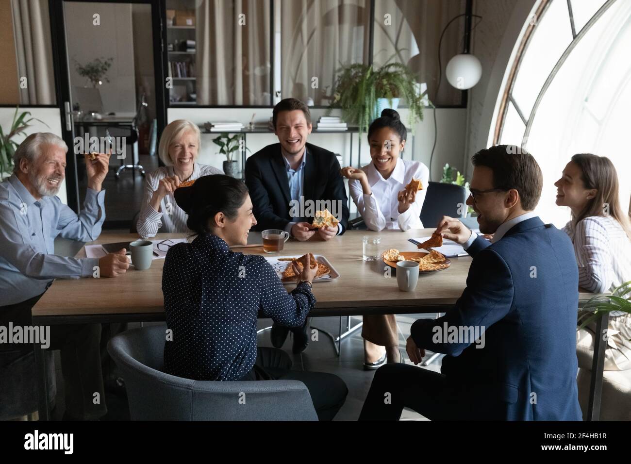 Happy multiethnic colleagues have fun lunching together Stock Photo