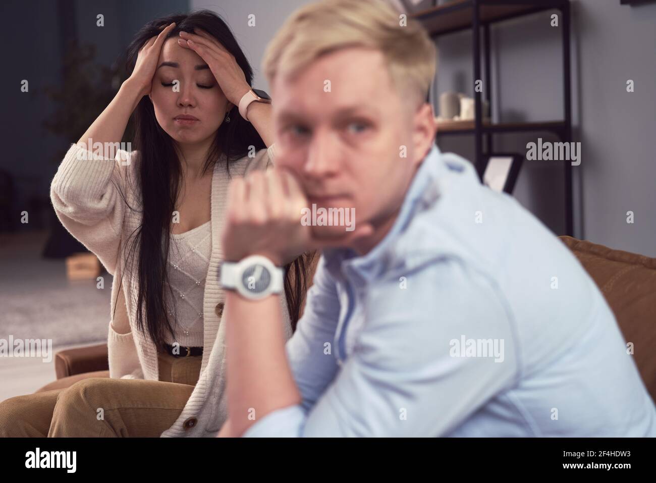 Unhappy Asian Woman taking to indifferent man during therapy session in office of psychologist Stock Photo