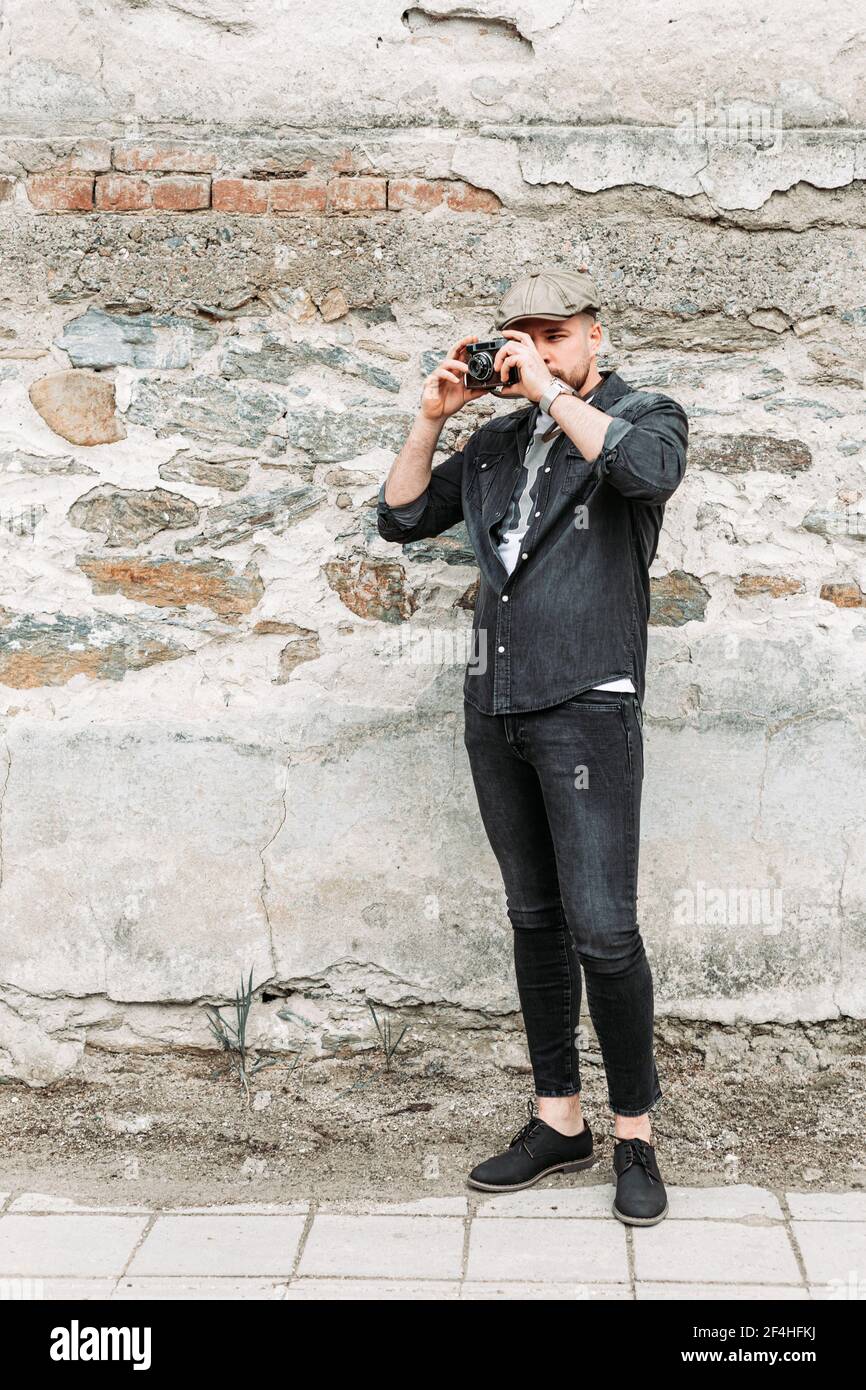 Young hipster man taking a photo with an old, retro camera. Copy space Stock Photo