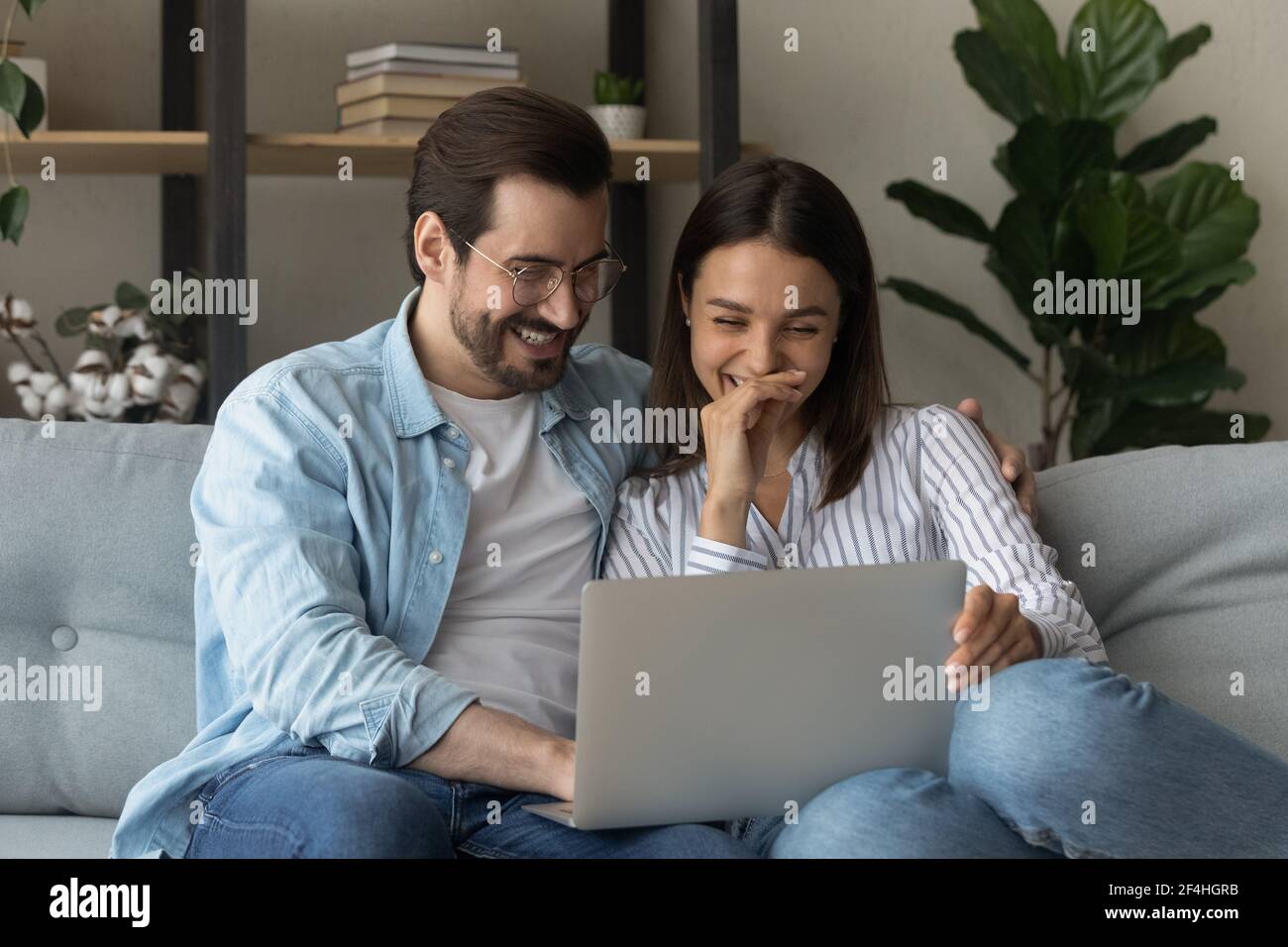 Close up happy laughing young couple watching video, using laptop Stock Photo