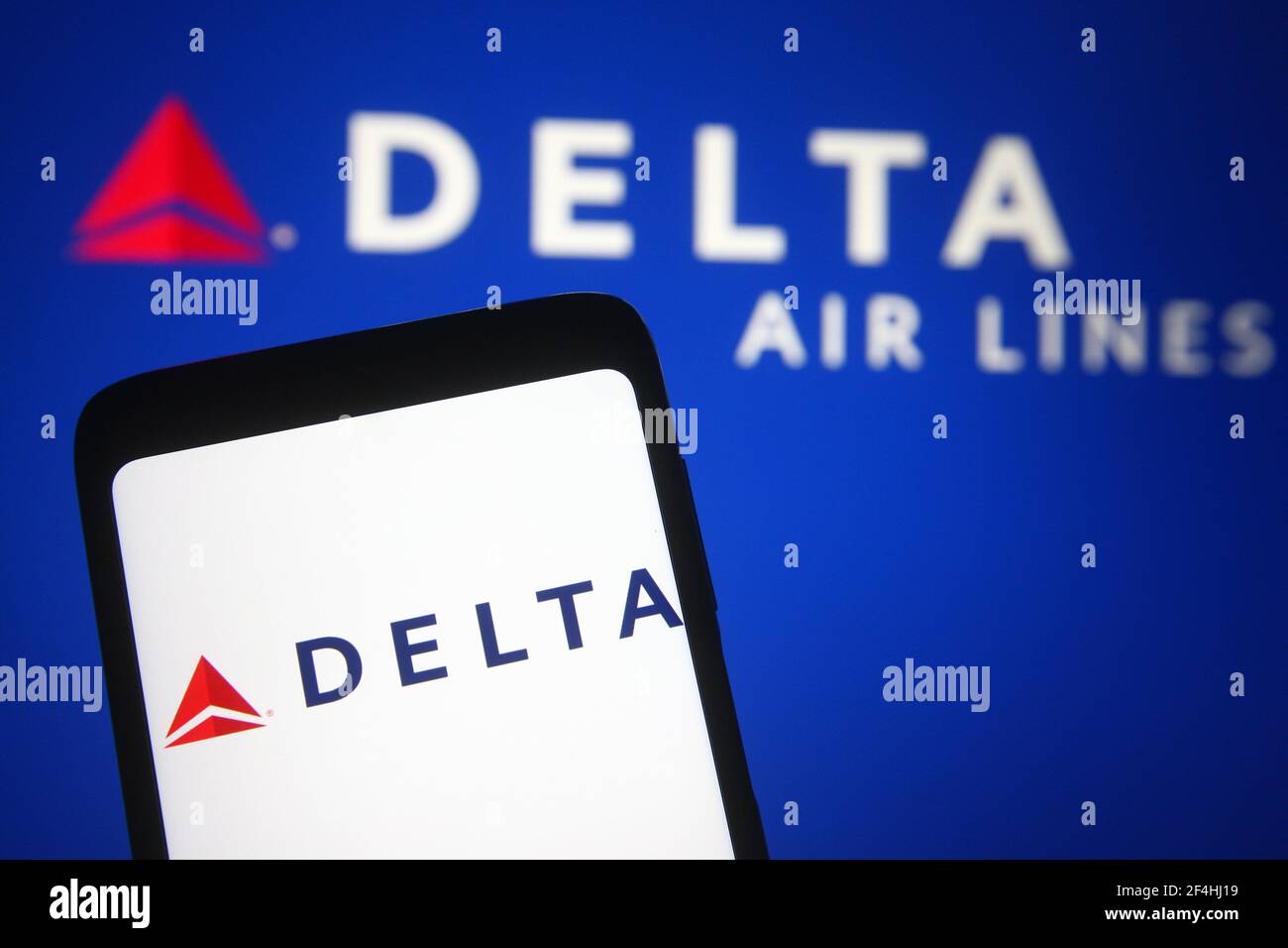 In this photo illustration a Delta Air Lines logo is seen on a smartphone and a pc screen. Stock Photo