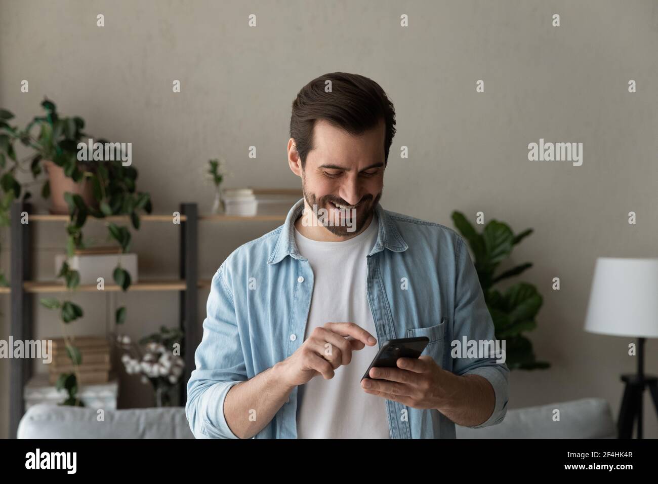 Close up smiling man using phone, browsing apps, having fun Stock Photo