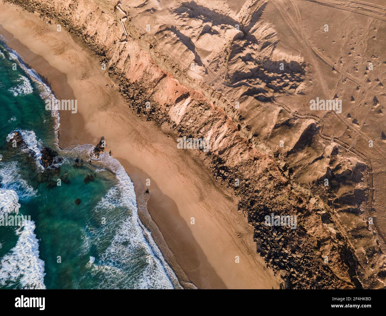 Beach shore under a cliff aerial overhead shot. Playa del Aguila beach, also known as La Escalera beach in Fuerteventura, Canary Islands Stock Photo