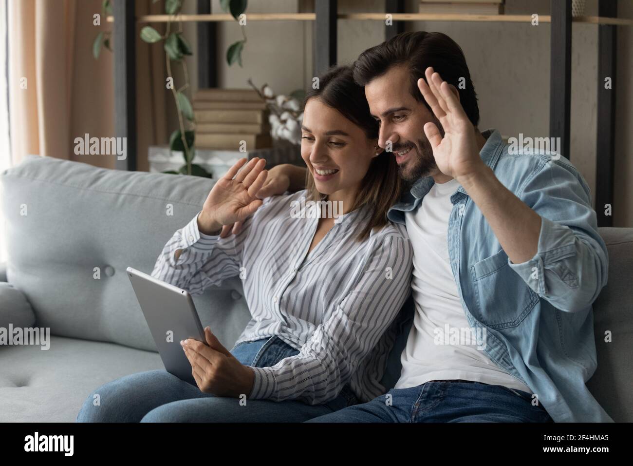 Close up smiling couple using tablet, waving hands, video call Stock Photo
