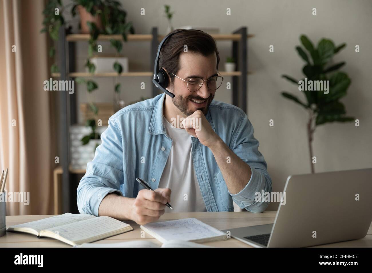 Close up smiling man wearing headphones involved in online lesson Stock Photo