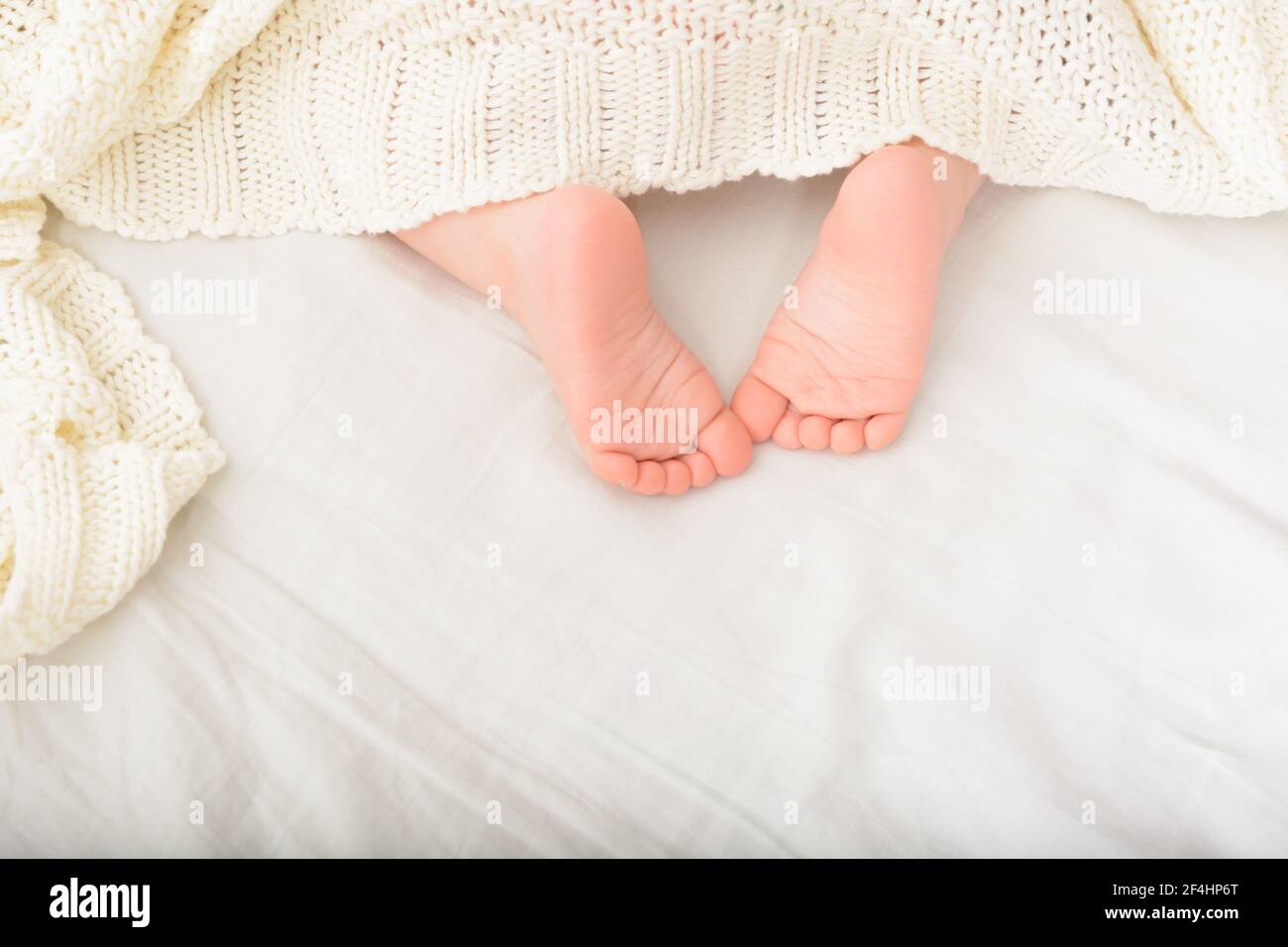 Feet of sleeping child in bed. Sweet baby part covered with soft