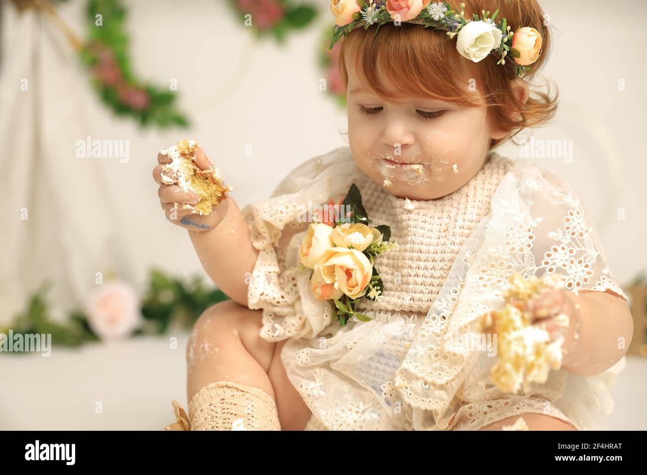 cute red haired baby girl smashes her first birthday cake Stock Photo