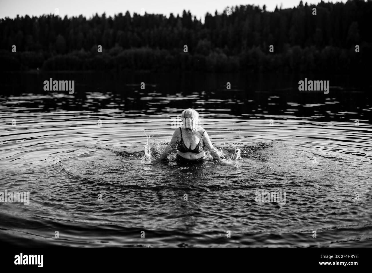An old woman in the river at summer. Black and white photo. Stock Photo
