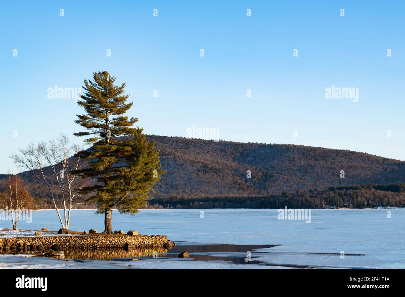 Osborne Point and Speculator Mountain on Lake Pleasant in Speculator, NY in late winter with ice still on the lake Stock Photo