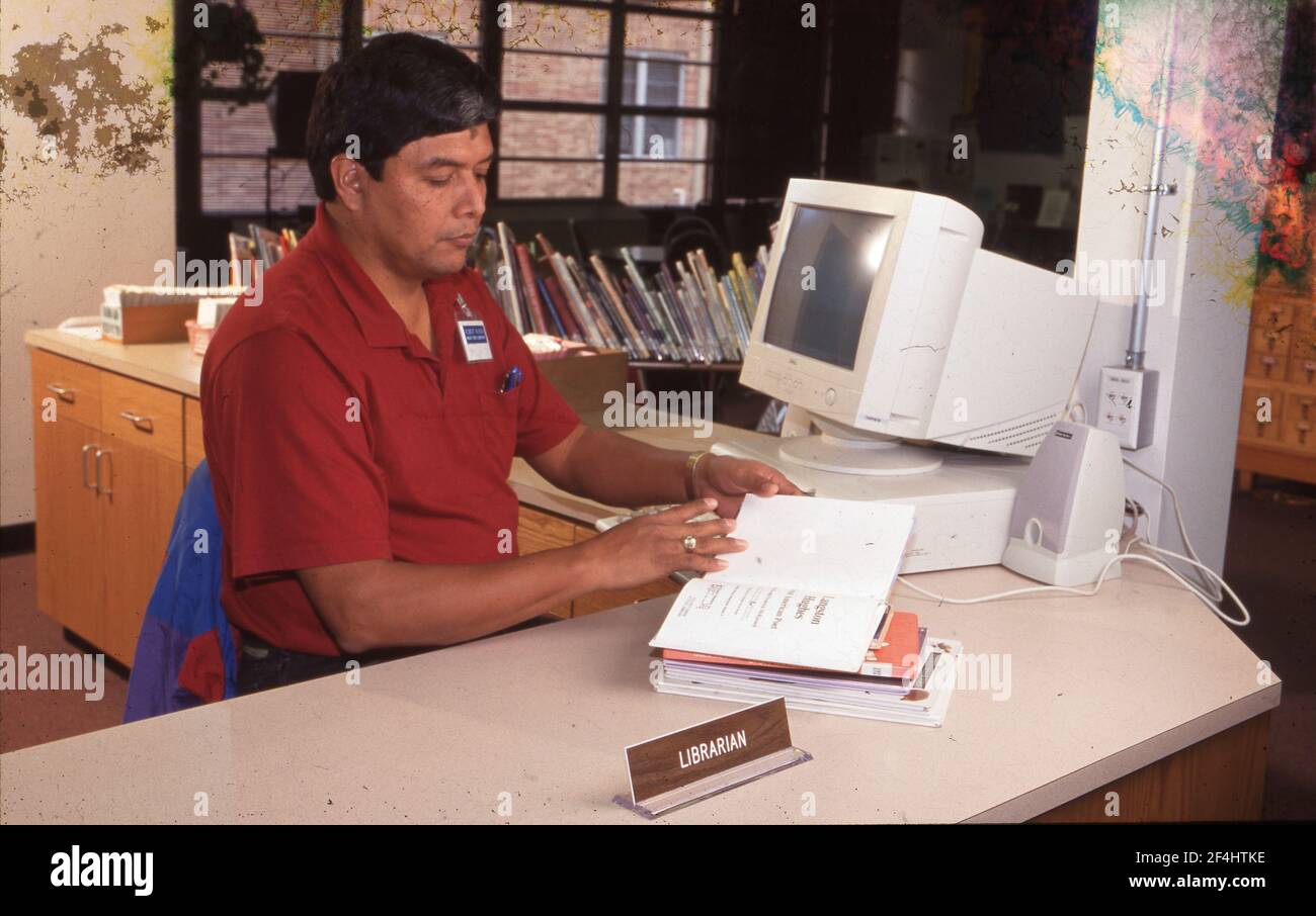 Hispanic man as librarian in an Austin, Texas elementary school. Stock Photo