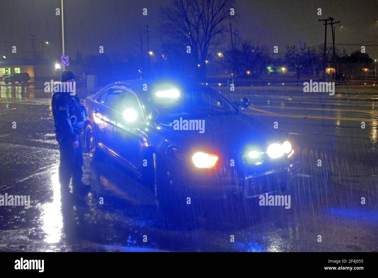 A Detroit police officer stands by his vehicle on a rainy night in Detroit, Michigan, USA Stock Photo