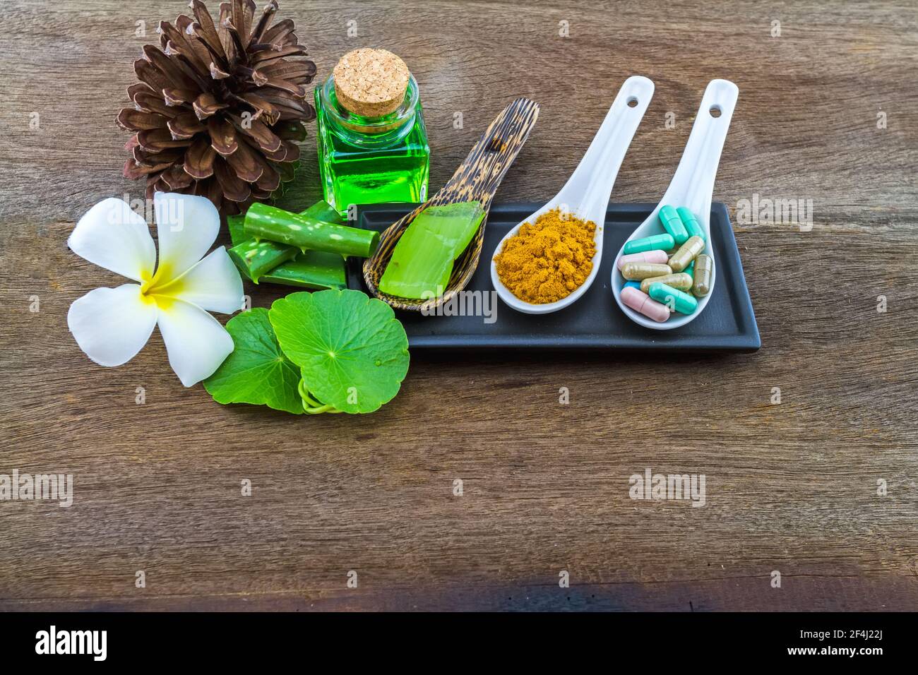 Spa herbal (white frangipani flowers, turmeric powder in white spoon ,pill,Aloe vera essential oil and gel,Green Asiatic Pennywort ) on wooden backgro Stock Photo