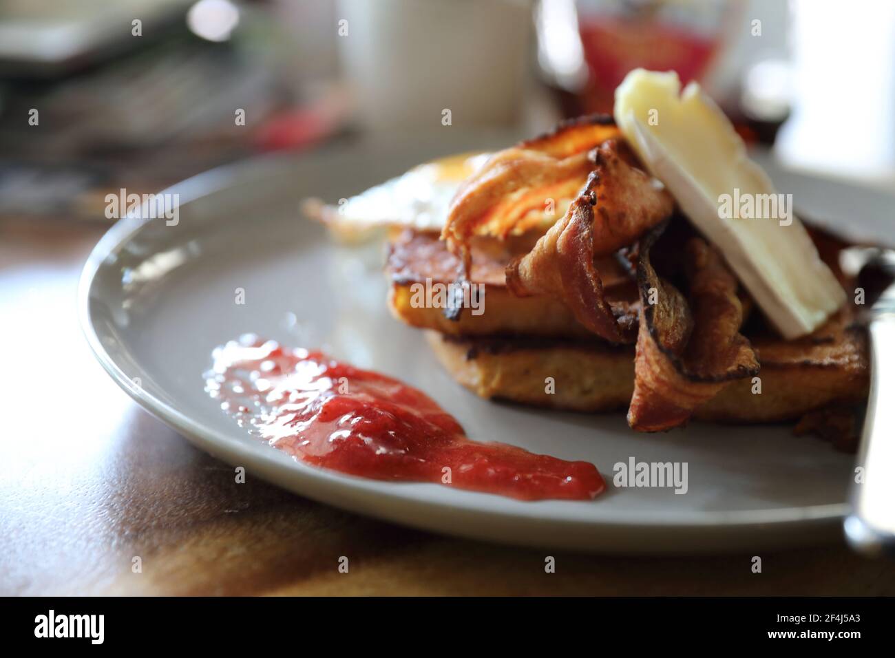 Breakfast french toast with bacon egg and cheese with jam on wood table