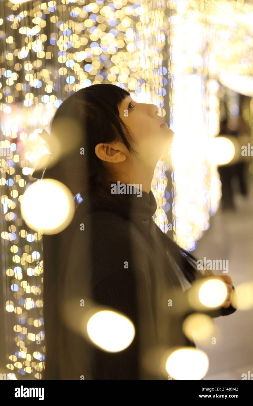 Young pretty girl wearing black cotton sweatshirt on bokeh background at night Stock Photo