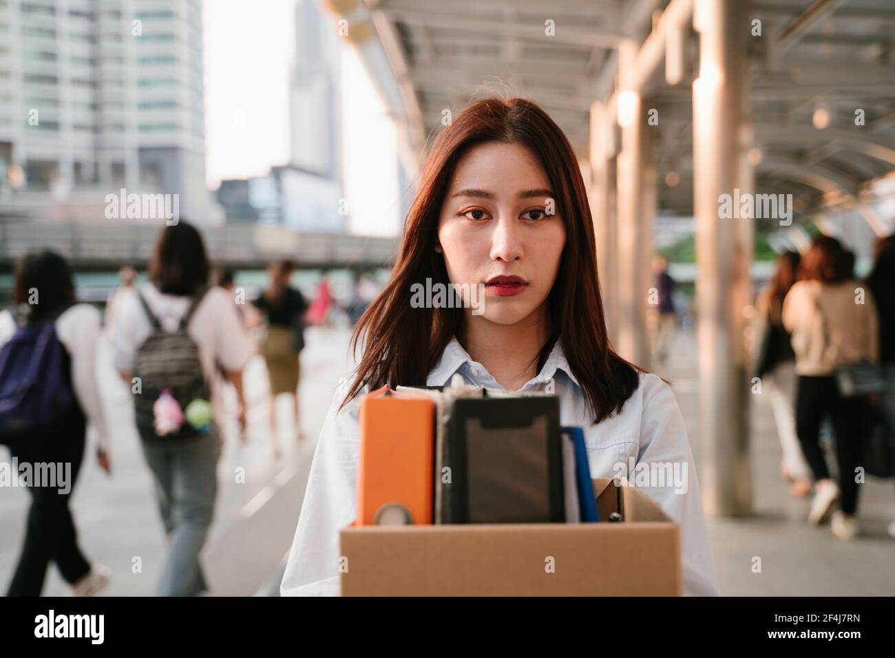 Portrait of young Asian woman holding box of items after being laid off from job due to recession and economic stress in industry Stock Photo