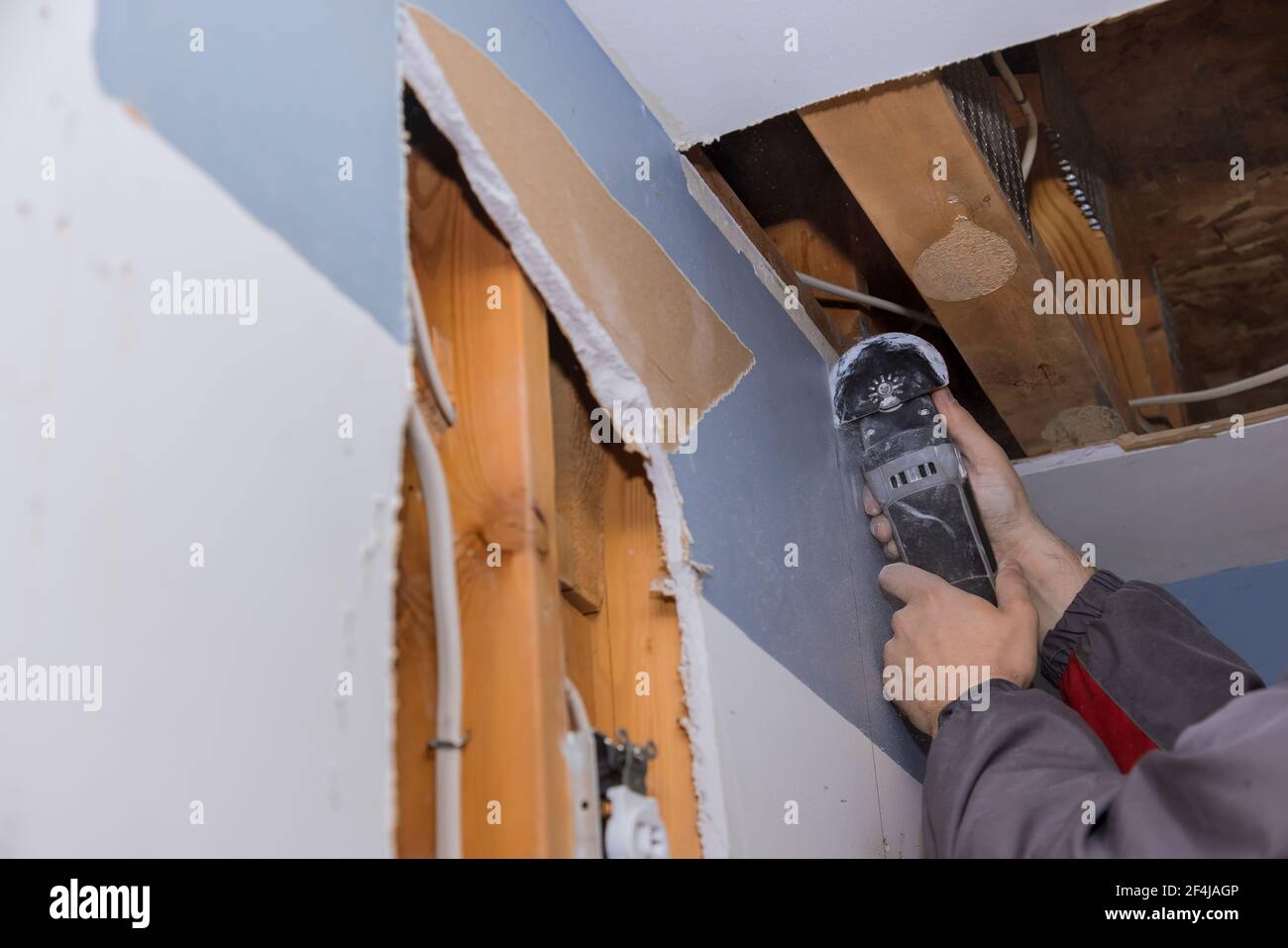 Damaged plasterboard with repair home of man cutting gypsum drywall on