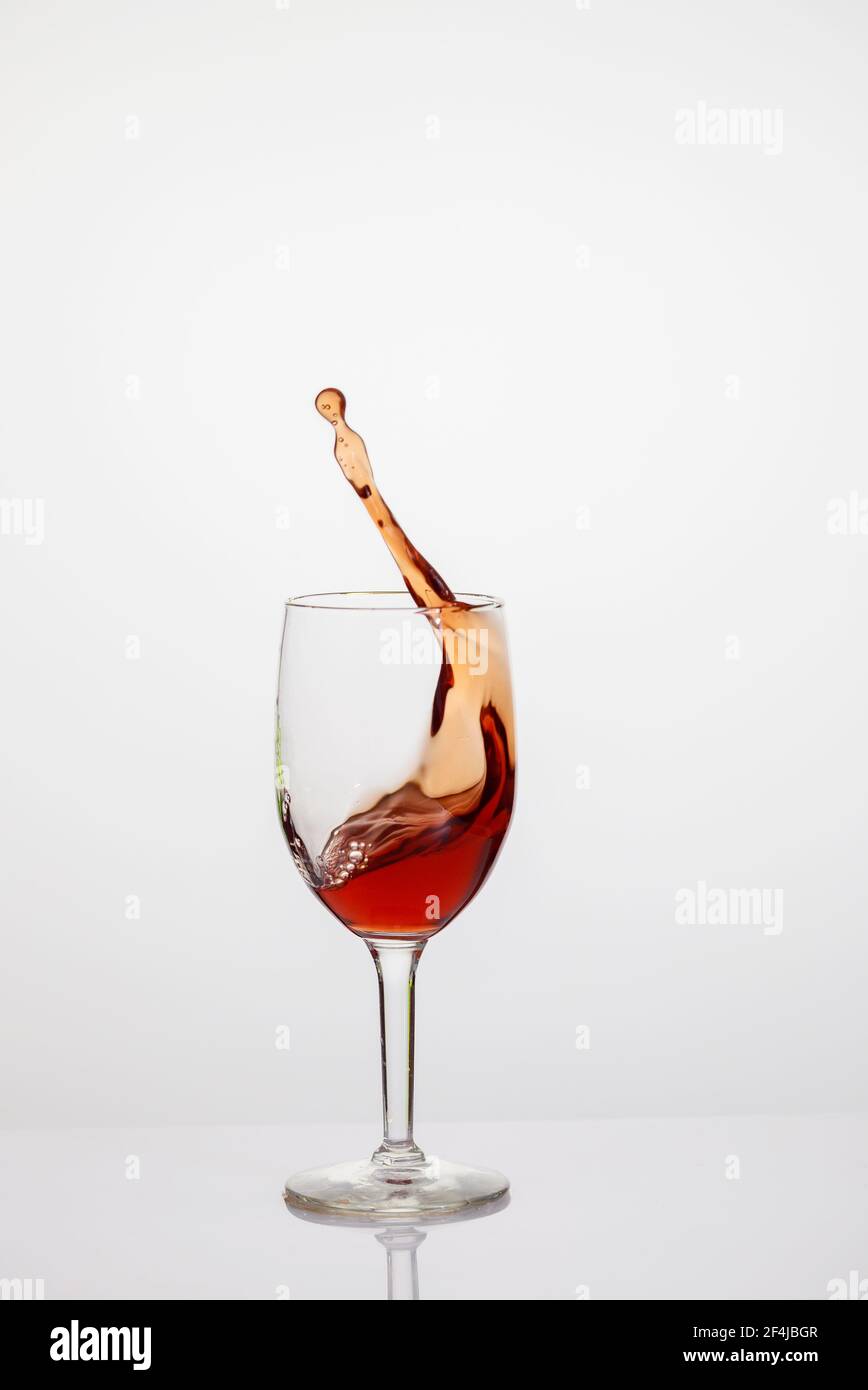Splash of red wine in glass on white background. Stock Photo