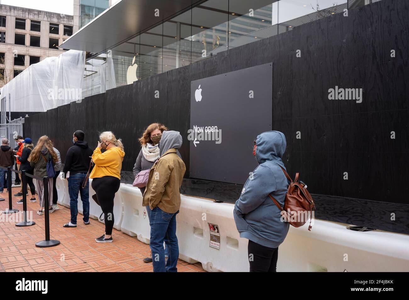 Masked shoppers who had made online reservations line up on Sunday, March 21, 2021, outside of the Apple Store Pioneer Place, which reopened on Feb 22... Stock Photo
