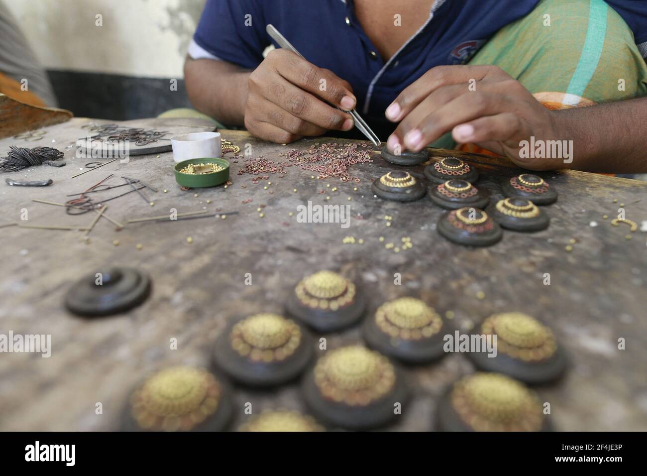 Workers make and sorting out copper and silver jewellery at Bhakurta village in Savar on the outskirts of Dhaka, Bangladesh, March 21, 2021. Thousands of pieces of flashy jewellery found at shops in the capital Dhaka are crafted in this village. Most people these days know the place as 'gohona gram' (jewellery village). Even though the jewellers say they have been living there for a few generations - nearly a century âÂ€Â“ it became well-known as gohona gram only two to three decades back. Making jewelleries is like a household chore in this village. Not just men, women and children also work Stock Photo