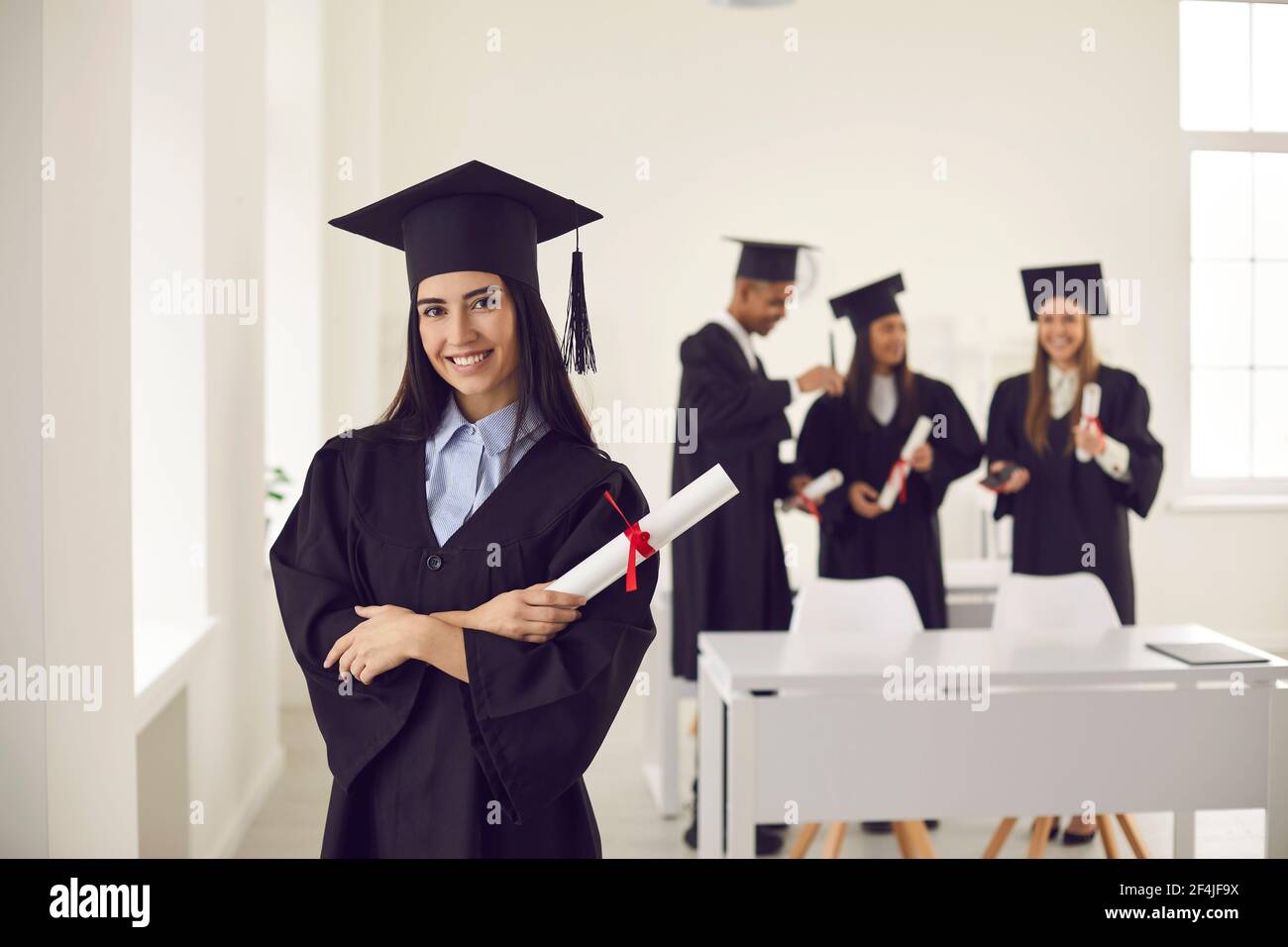 Pretty smiling caucasian girl student university graduate in mantle and bonet standing with diploma Stock Photo