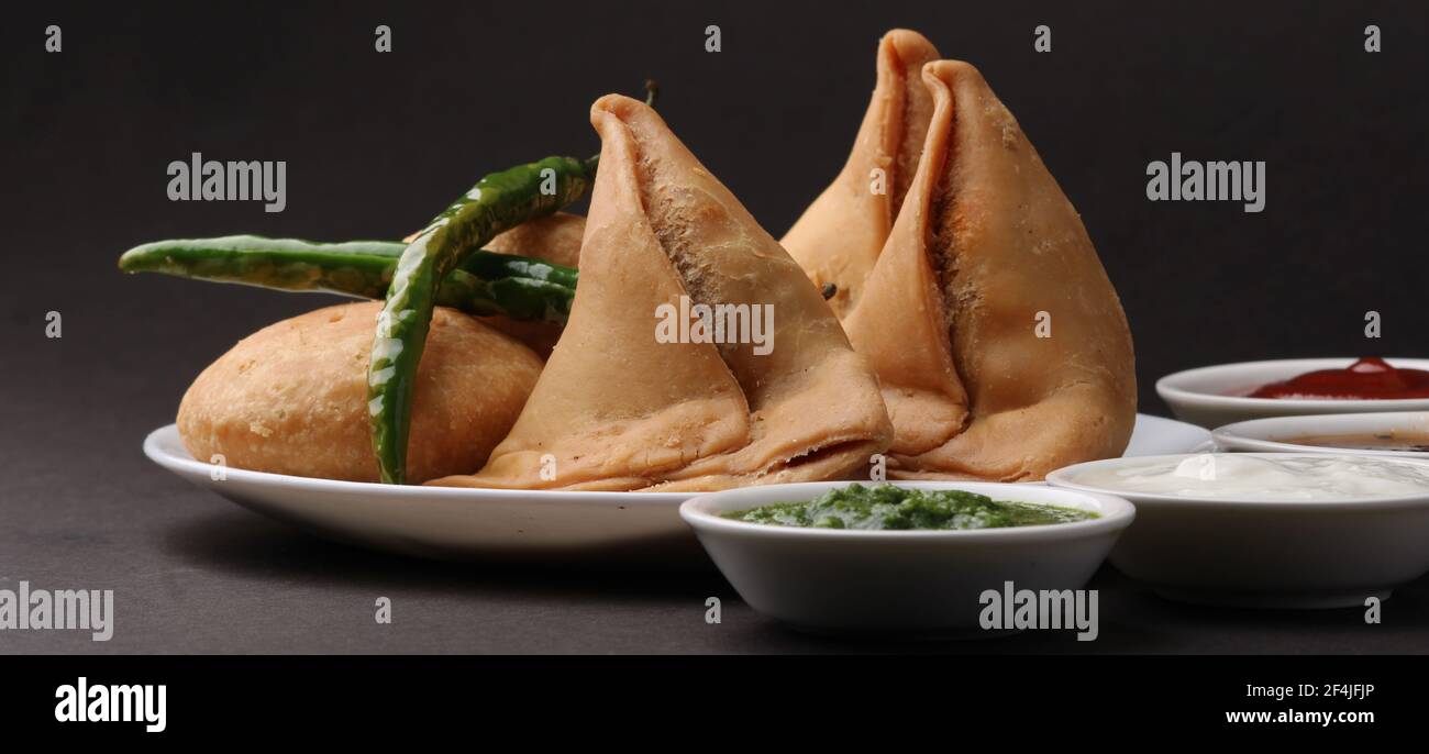 Kachori and samosa, Indian vegetarian snacks served with green and tamarind chutneys. Stock Photo