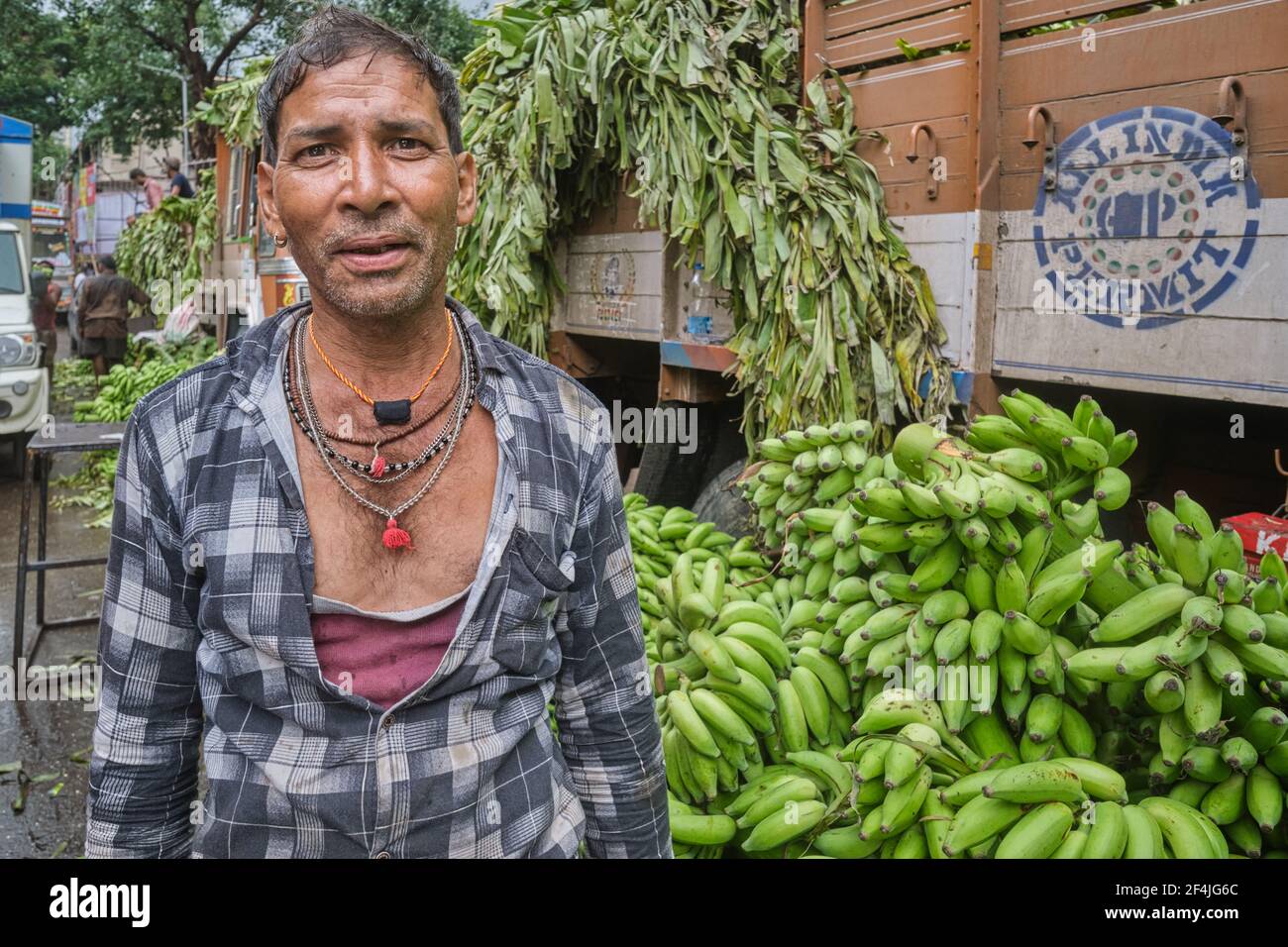 An employee of a transport company standing next to his truck and a delivery of bananas at Matunga Market in Mumbai, India Stock Photo