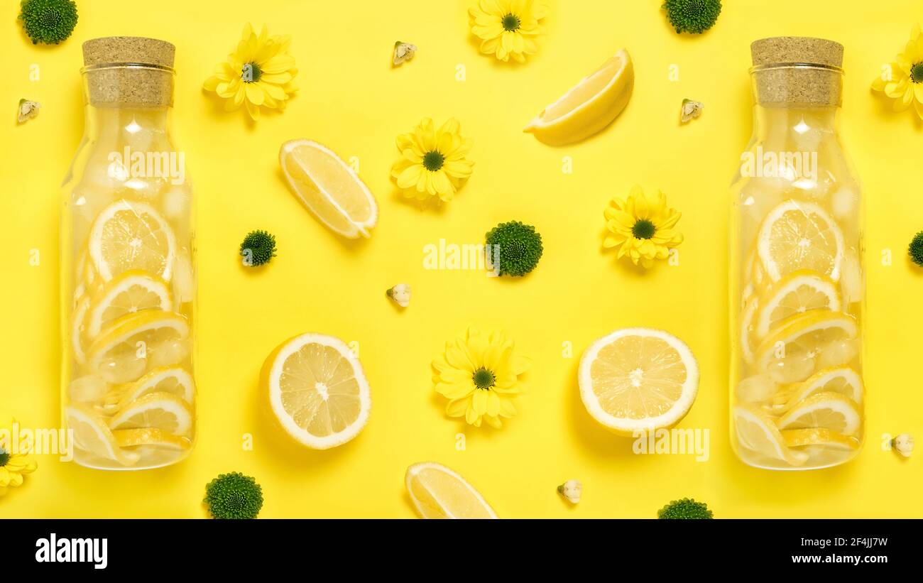 Flat lay Lemonade in glass bottles with lemons, flowers yellow paper background Stock Photo