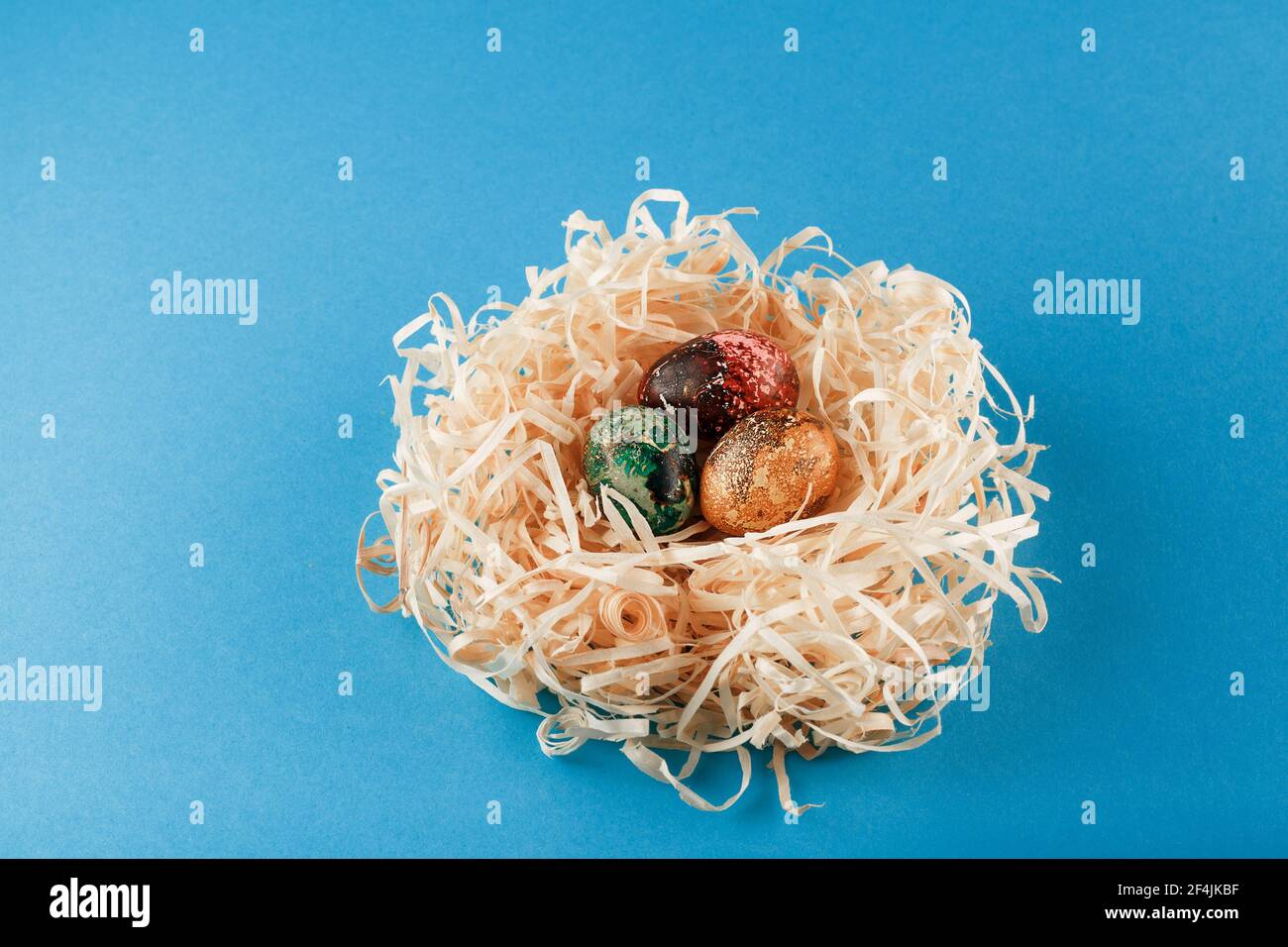 Three easter eggs are painted in red, yellow and green. Eggs lie in a ...