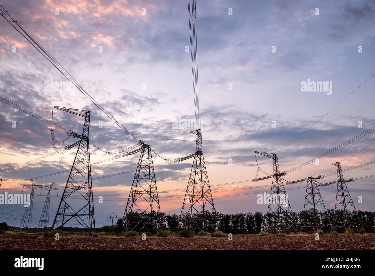 Electrical pylons and high voltage power lines at sunset background. Group silhouette of transmission towers. Stock Photo