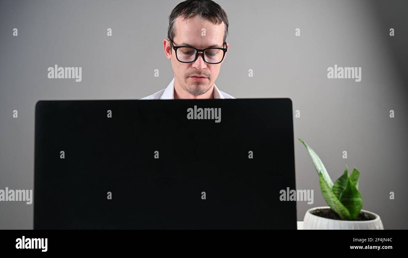 Young man in glasses works at the computer, front view . High quality ...