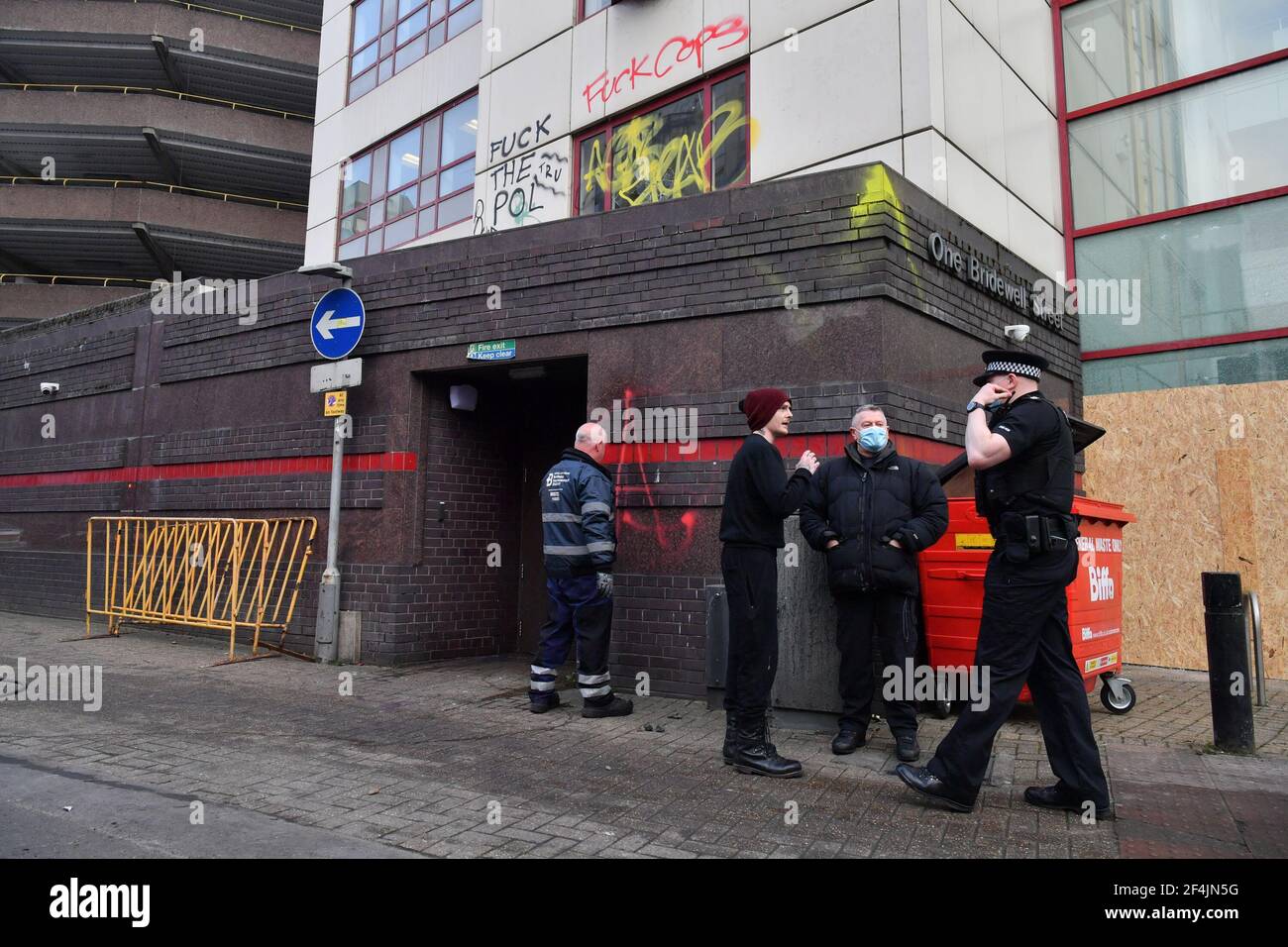 A police officer (right) speaks to a man (in red hat) after he confronted members of the media outside Bridewell Police Station in Bristol. Protesters broke windows and vandalised the police station on Sunday after demonstrating against the Government's controversial Police and Crime Bill. Picture date: Monday March 22, 2021. Stock Photo