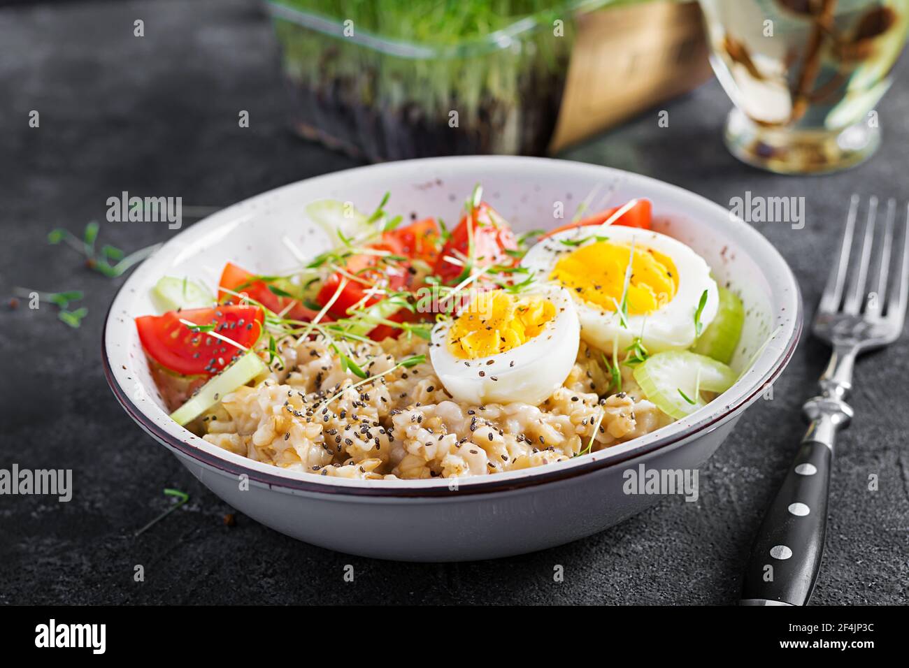 Breakfast oatmeal porridge with boiled egg, cherry tomatoes, celery and
