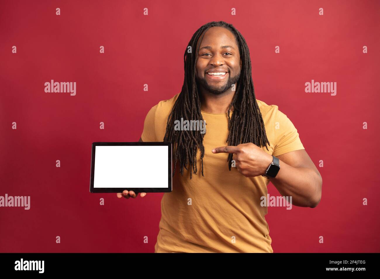 Mixed-race black man with dreadlocks standing isolated over red background,  presenting new application, pointing with finger on digital tablet with  white blank space for advertisement, mockup image Stock Photo - Alamy