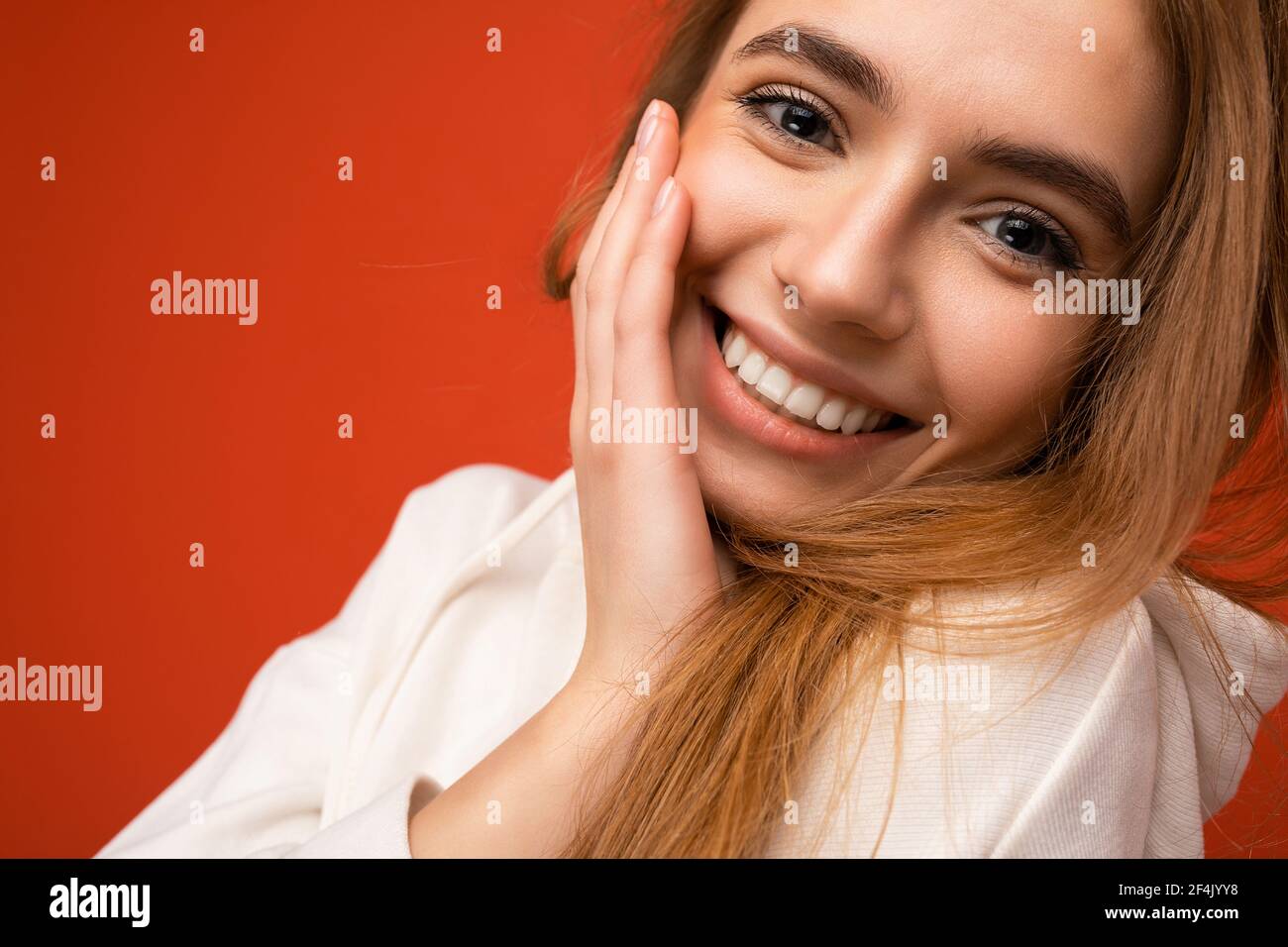 Closeup portrait of young smiling beautiful dark blonde woman with sincere emotions isolated on background wall with copy space wearing casual white Stock Photo